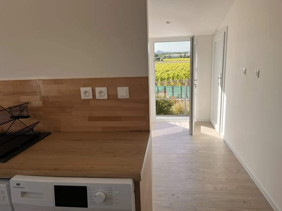 Cuisine équipée de l'appartement T2 avec lave-linge et vue vignes